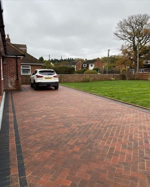 White car parked on red brick driveway of suburban home