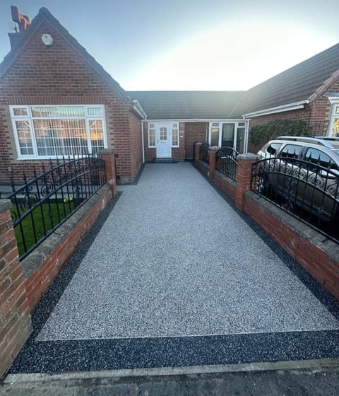 Brick residential home with driveway, black metal gates on both sides