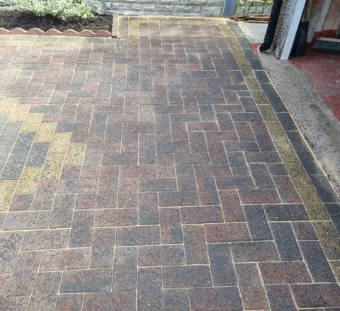 Outdoor patio with herringbone-patterned brick pavers in red and gray tones