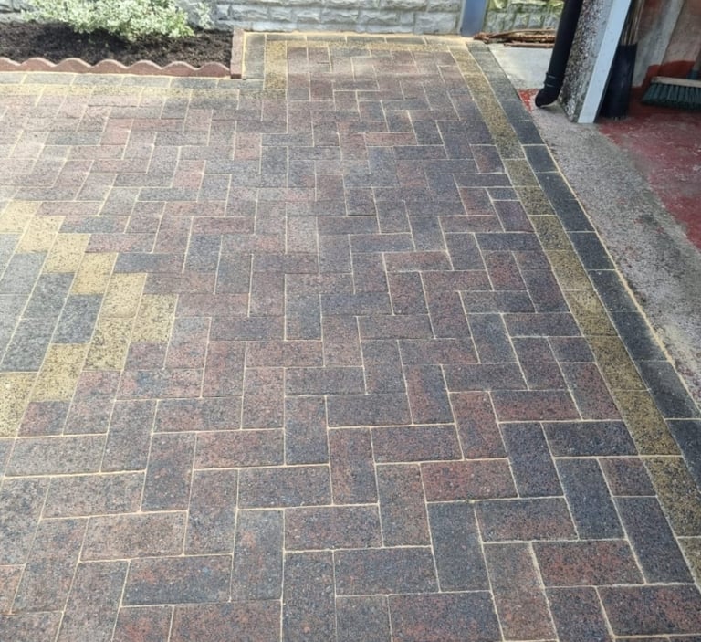 Outdoor patio with herringbone-patterned brick pavers in red and gray tones, bordered by yellow lines